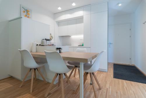 a kitchen with a wooden table and white chairs at Grüne Oase an der Therme in Vienna