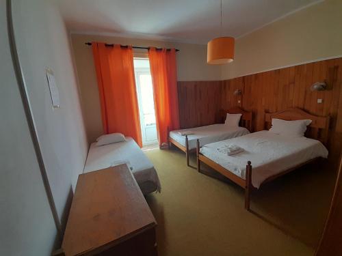 ラゴスにあるCaravelaのベッド2台とオレンジのカーテンが備わるホテルルームです。