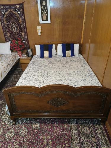 a bedroom with a wooden bed with blue pillows at Houseboat New Suzan in Srinagar