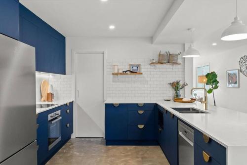 a kitchen with blue cabinets and a white wall at Salty Crab Bungalow in Lennox Head