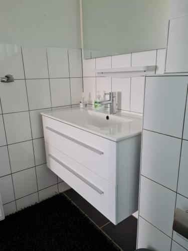 Baño blanco con lavabo y espejo en Ferienwohnung in Fuldatal bei Kassel en Fuldatal