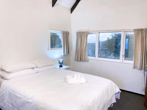 een slaapkamer met een wit bed en 2 ramen bij NO PARTY ALLOWED,Sea view 5 bedroom house in Wellington