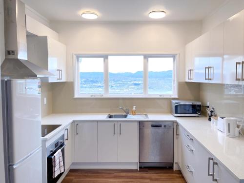 a kitchen with white cabinets and a sink and a window at NO PARTY ALLOWED,Sea view 5 bedroom house in Wellington