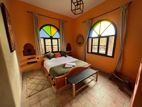 a bedroom with a bed and two windows at Villa Nouran - Chambre Hôte in Ghazoua