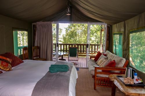 a bedroom with a bed and a living room at Fernhill Tented Treehouses in Rheenendal