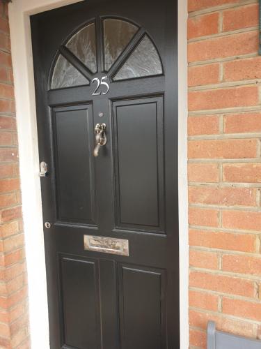 een zwarte deur op een bakstenen gebouw met een baksteen bij Pinewood Studios, Iver near Heathrow and Windsor XL 75sqm 2 King Bed Flat with 2 Parking Spaces in Buckinghamshire