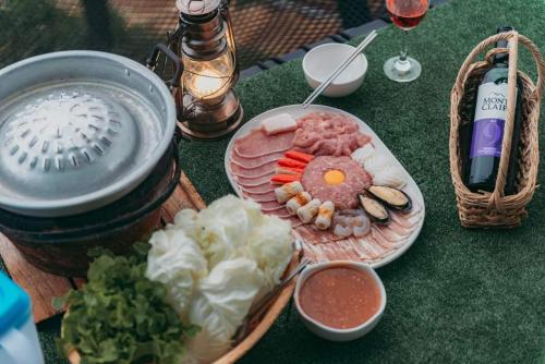 a table with a plate of food and a bottle of wine at ภูตะวัน-บ้านท่าจัน ม่อนแจ่ม in Mon Jam