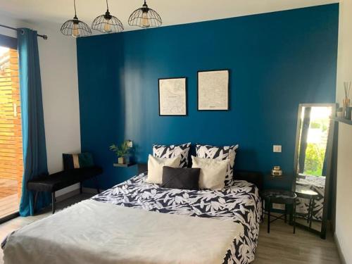 Un dormitorio con una pared azul y una cama en Appartement proche Astérix, Stade de France, Chantilly, Roissy, piscine saisonnière en La Chapelle-en-Serval