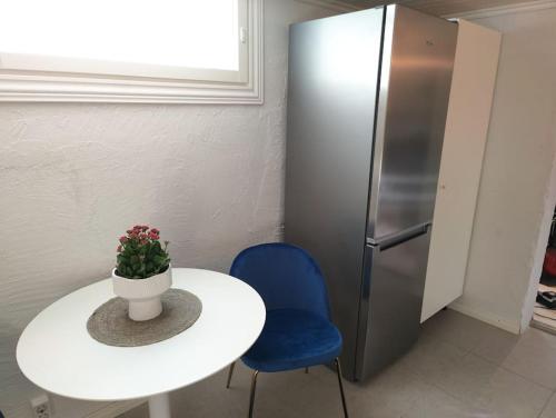 a table and a blue chair and a refrigerator at Yksityinen kellarikerros omalla sisäänkäynnillä, Pietarsaari in Pietarsaari