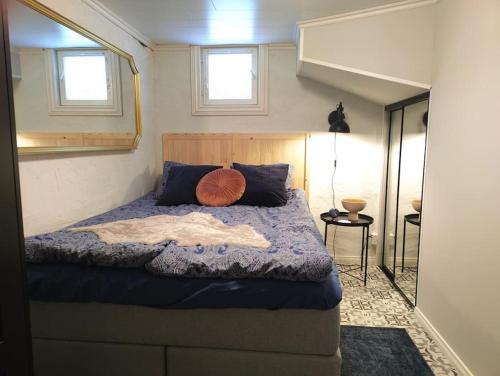 een slaapkamer met een bed met een blauw dekbed en 2 ramen bij Yksityinen kellarikerros omalla sisäänkäynnillä, Pietarsaari in Pietarsaari