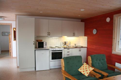 uma cozinha com armários brancos e cadeiras verdes num quarto em Hornborgasjöns Stugby em Bjällum