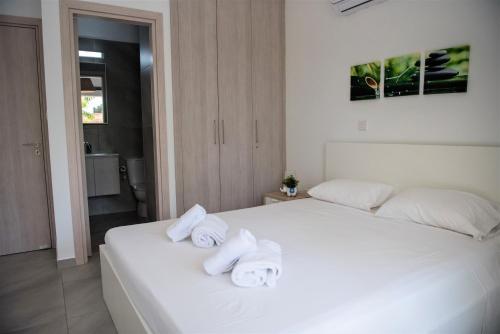 a bedroom with a white bed with towels on it at Carme at the Beach - Mythical Sands in Paralimni
