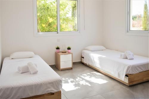 two beds in a room with two windows at Carme at the Beach - Mythical Sands in Paralimni
