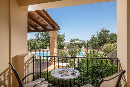 balcón con mesa, sillas y piscina en Gerani Villas, en Gerani