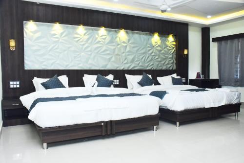 two beds in a bedroom with a large screen at Hotel La Gowri, Coorg in Madikeri