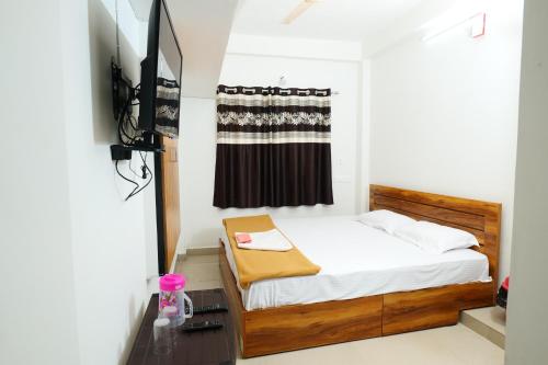 a small bedroom with a bed and a television at Hillside Hideaway Gudalur in Gūdalūr
