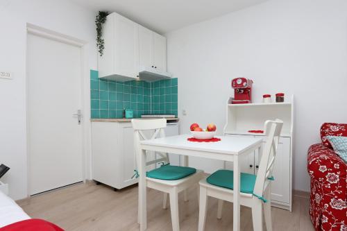a small kitchen with a white table and chairs at Sha La La - Charming, unique studio in a historic building next to a castle, WIFI, smart TV, washer-dryer in Bakar