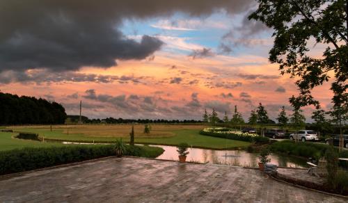 a sunset over a golf course with a pond at Country Lodge Hotel Moriaanshoofd in Oudenaarde