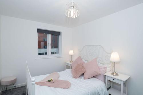Dormitorio blanco con cama blanca y almohadas rosas en Central Gunwharf Quays Two Bedroom apartment, en Portsmouth