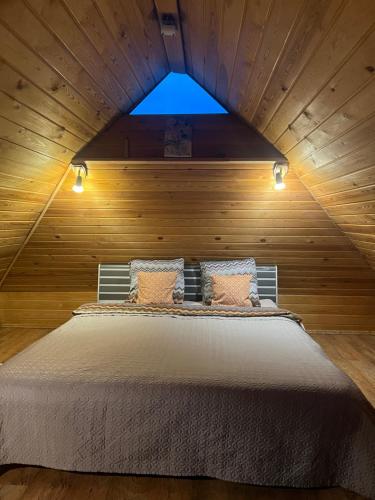 een bed in een houten kamer met een raam bij Pirtiņa in Ogre
