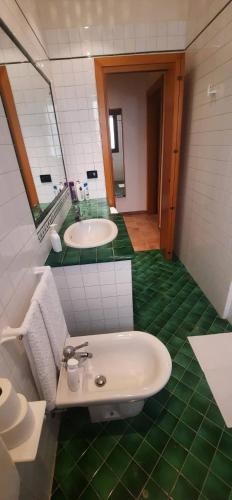 a bathroom with two sinks and a green tiled floor at Sarika House in Mestre