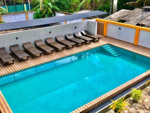 a swimming pool with chairs in a resort at Sundowners Guesthouse in Hikkaduwa