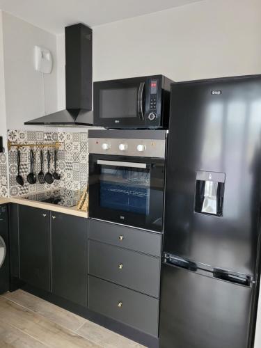 une cuisine avec un réfrigérateur en acier inoxydable et un micro-ondes dans l'établissement Appartement rénové près république, à Dijon