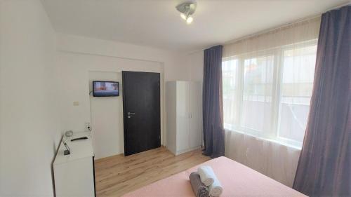 a room with a bed and a door with a television at 3 Rooms Apartment, Top Center, 1st Floor, AUBG, WiFi, PC i5 SSD, Tablet, AndroidMiTvBox, 3 LED TVs 200 Channels, Long Terrace, Self-Easy-Late Check-in, Stay Before Greece in Blagoevgrad
