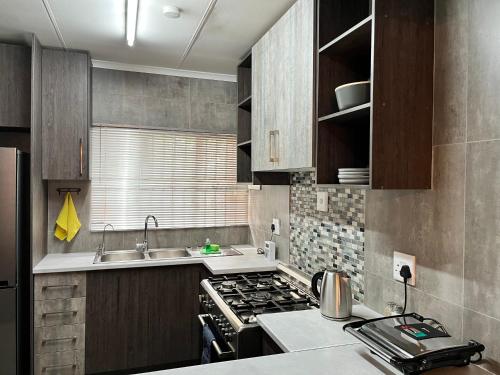 a small kitchen with a stove and a sink at UStay Apartment - Westdene in Bloemfontein
