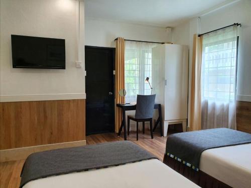 a hotel room with two beds and a desk with a television at Holiday Village And Natural Garden Resort in Karon Beach