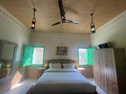 a bedroom with a bed with green shutters and a ceiling at Al Bait resort with private swimming pools -HRS stables in Al Ḩamrānīyah