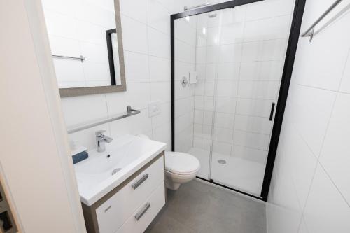 a white bathroom with a toilet and a shower at 4flats in Maribor