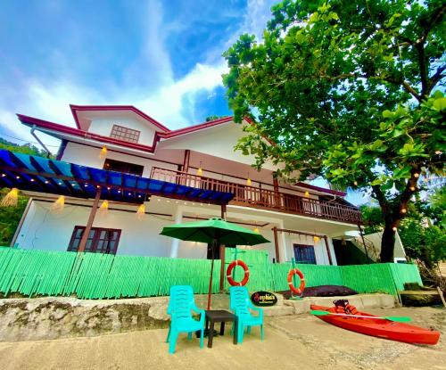 a house with two chairs and an umbrella on the beach at Sophias Beach Guest House in El Nido