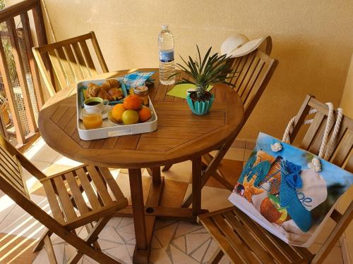 a wooden table with a tray of fruit on it at LOGEMENT AZUL à l'ombre du bambou 1 à 3 pers, Réserve Cousteau in Le Gosier