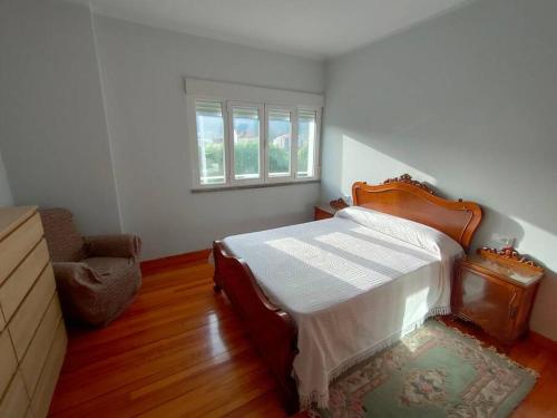 a bedroom with a bed and a chair and a window at Outes centro in Sierra de Outes