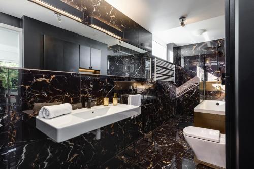 a black bathroom with two sinks and a toilet at Luxury Apartment Pogorzelica in Pogorzelica