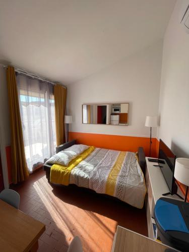 une chambre avec un lit avec un mur orange dans l'établissement T2 avec terrasse, vue étang et son coucher de soleil, plage à proximité, wifi et place de parking gratuit que l on nomme Puesta de Sol, au Barcarès