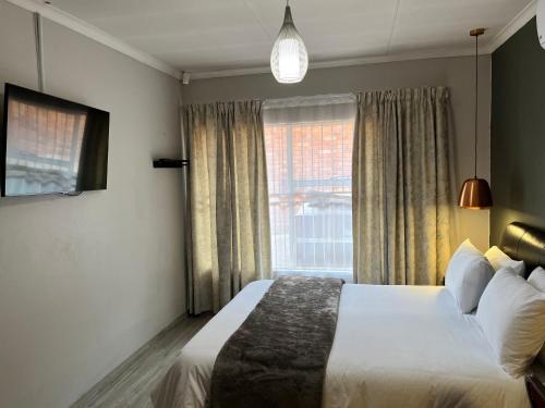 a hotel room with a bed and a window at UStay Apartment - Westdene in Bloemfontein