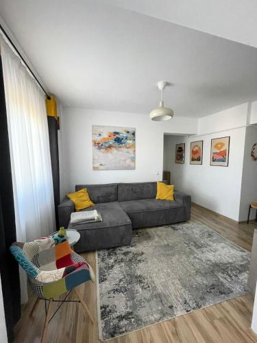 a living room with a gray couch and yellow pillows at Cozy Apartment - near Airport and Palas Mall in Iaşi