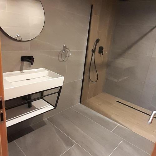 a bathroom with a shower and a sink and a mirror at Apartmán 107 Hotel Ovruč in Štrbské Pleso