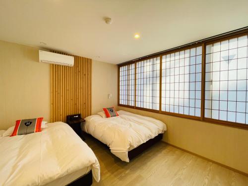 - 2 lits dans une chambre avec de grandes fenêtres dans l'établissement 東瀛Stays402奈良　お洒落な和洋室, à Osaka