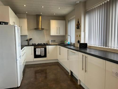 a kitchen with white cabinets and black counter tops at Seapoint House in Cleveleys