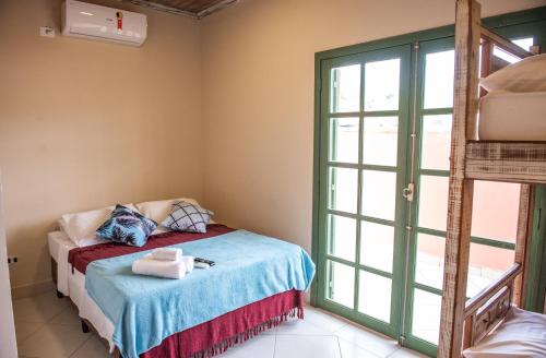 a bedroom with a bed and a large window at Pousada Casa Rosada Ilhabela in Ilhabela