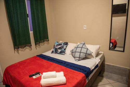 uma cama com toalhas e um controlo remoto em Pousada Casa Rosada Ilhabela em Ilhabela