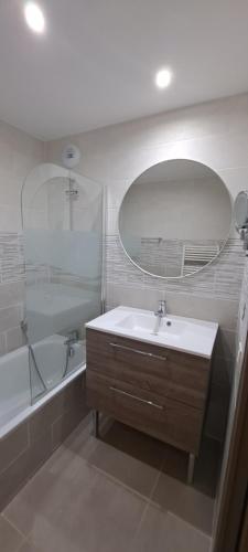 uma casa de banho com um lavatório, uma banheira e um espelho. em Appart T2 standing tout confort avec balcon - parking en option em Lyon