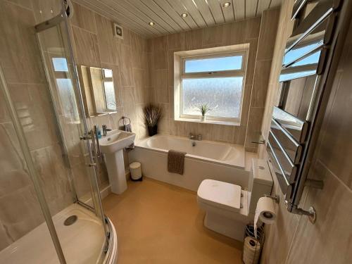 een badkamer met een bad, een toilet en een wastafel bij Seapoint House in Cleveleys