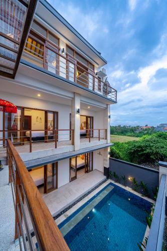 a house with a swimming pool and a balcony at Kasmaran Bali Guest House in Munggu