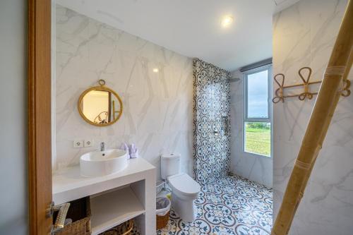 a bathroom with a sink and a toilet and a mirror at Kasmaran Bali Guest House in Munggu