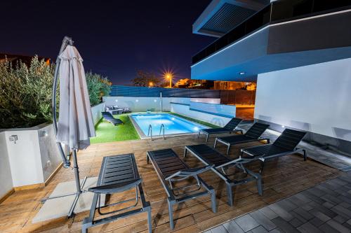 a patio with chairs and a swimming pool at night at Villa Porta Salonae in Solin