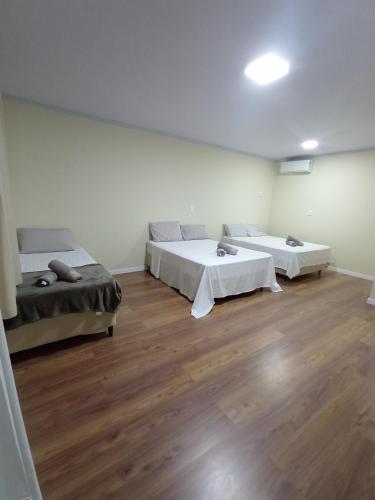 zwei Betten in einem großen Zimmer mit Holzboden in der Unterkunft Pousada Leal in Penha